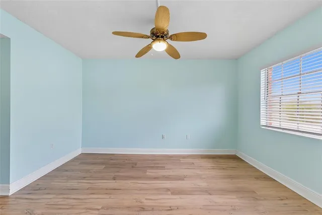 a view of an empty room with wooden floor and a window