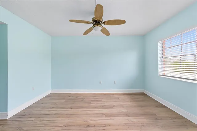an empty room with wooden floor fan and a window