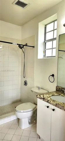 a bathroom with a granite countertop toilet a sink and shower