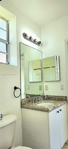 a bathroom with a granite countertop sink a toilet and mirror