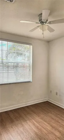 en empty room with wooden floor and fan