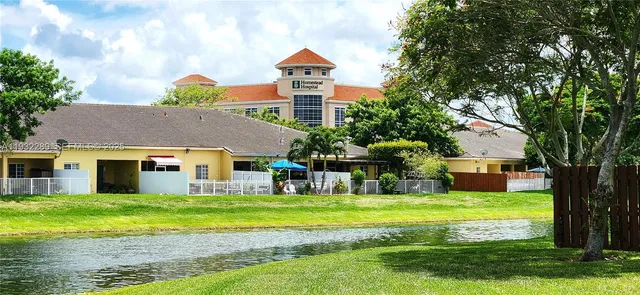 a view of a house with a big yard and large trees