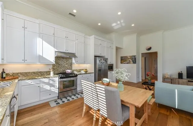 a kitchen with refrigerator a stove a sink and white cabinets with wooden floor