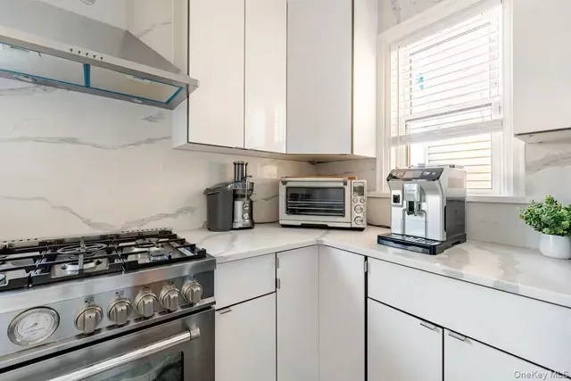 a kitchen with stainless steel appliances a sink a stove and white cabinets