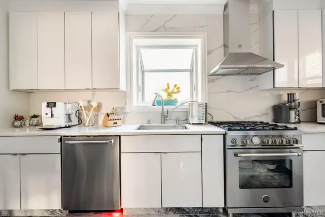a kitchen with stainless steel appliances granite countertop a stove a sink and white cabinets