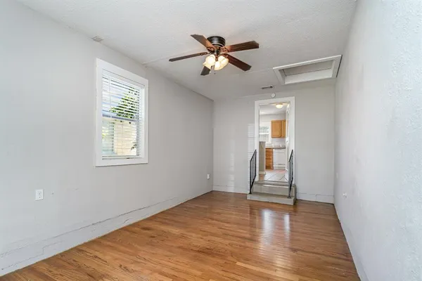 a view of empty room with wooden floor and fan