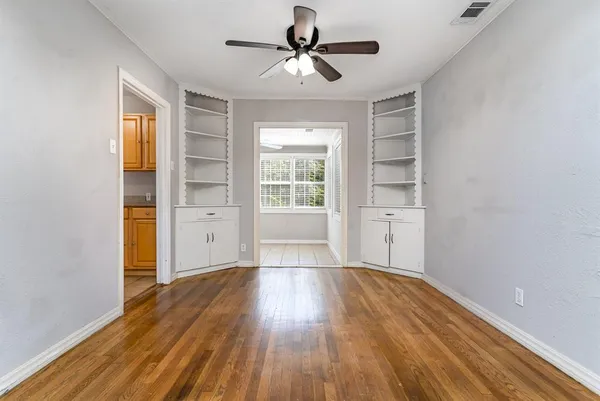 a view of empty room with wooden floor and fan