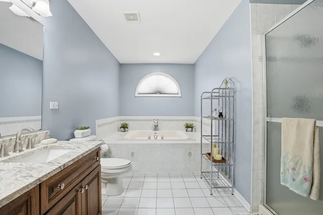 a spacious bathroom with a granite countertop sink a toilet and a bathtub