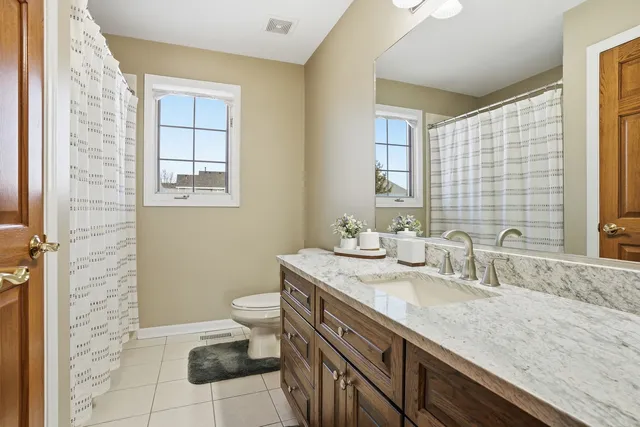 a bathroom with a granite countertop sink a toilet and a mirror