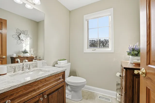 a bathroom with a granite countertop sink a toilet a mirror and shower curtain
