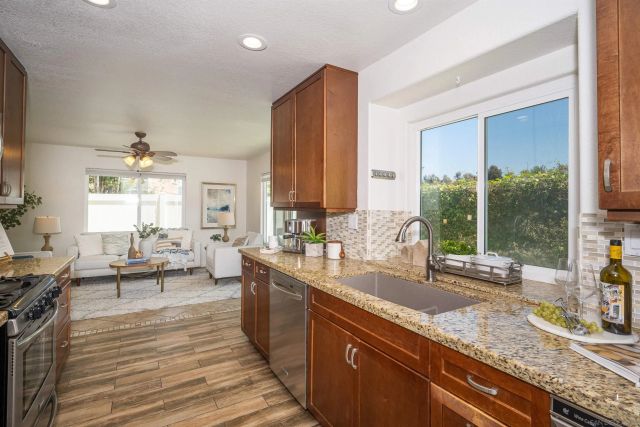 a view of a kitchen counter top space with granite countertop wooden floor and stainless steel appliances