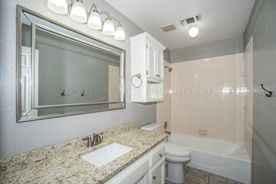 7909 Triumph Place Amarillo, TX 79119 - Photo 9 of 21 a bathroom with a granite countertop sink a toilet and shower