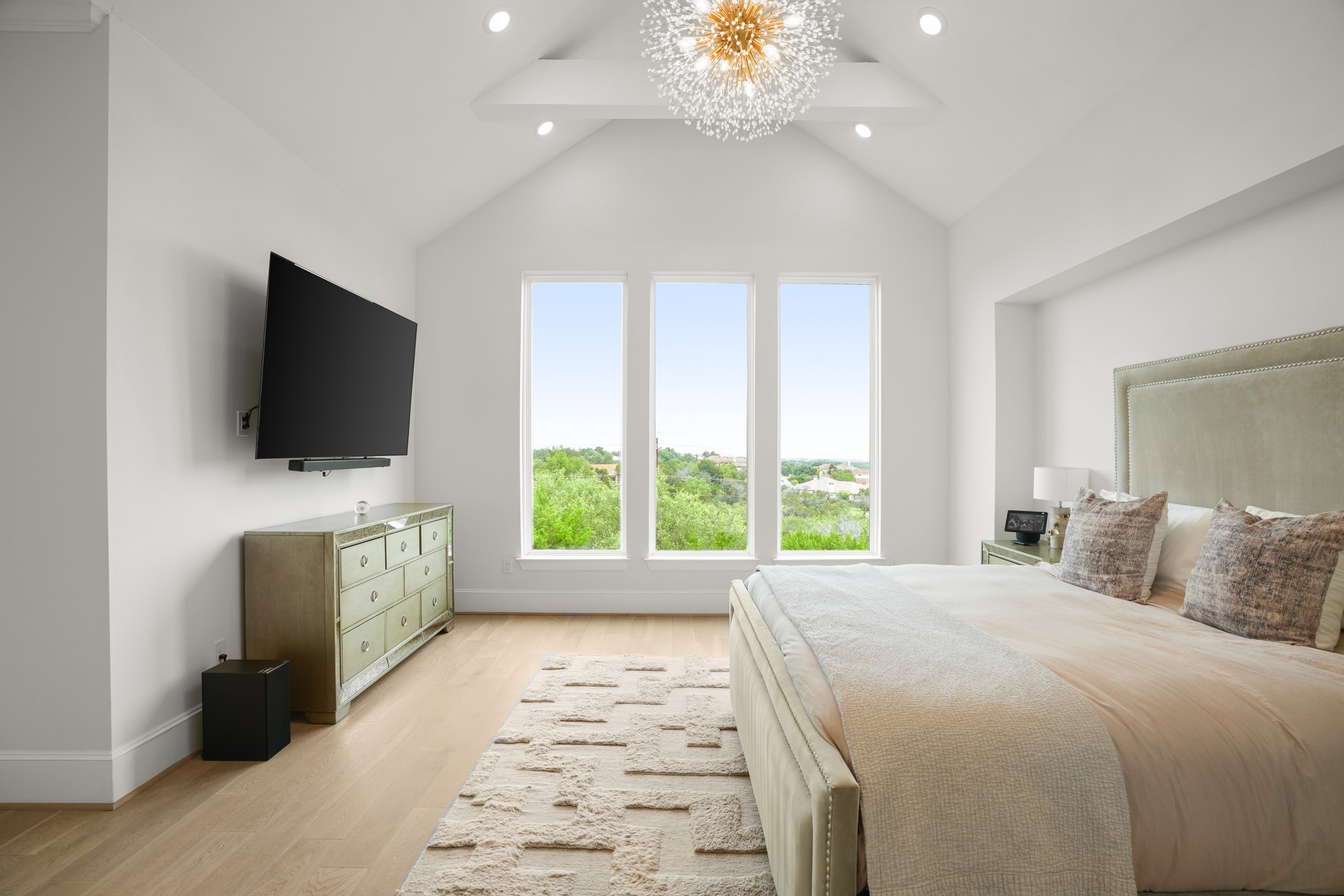 104 Lodestone Cove Austin, TX 78738 - Photo 18 of 40 A spacious primary bedroom with soaring vaulted ceilings offers natural light and verdant outdoor views.