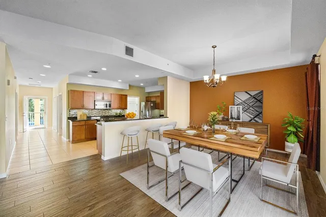 a kitchen with stainless steel appliances kitchen island granite countertop a stove a sink a refrigerator and white cabinets with wooden floor