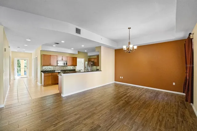 a view of kitchen with refrigerator a stove and wooden floor