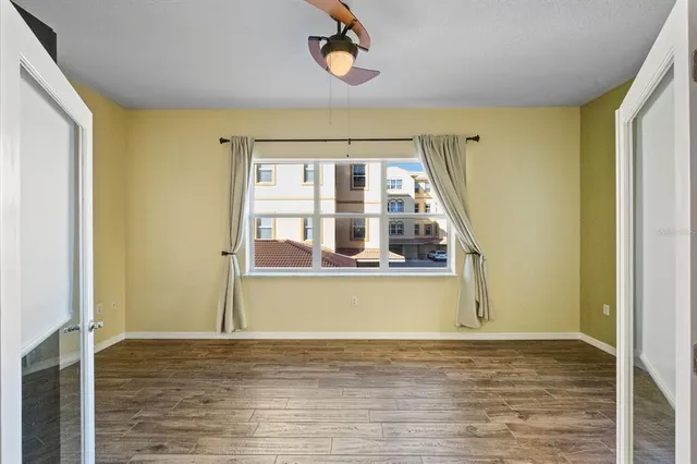 a view of empty room with wooden floor and fan
