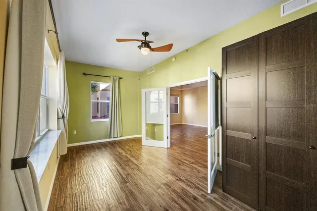 a view of an empty room with wooden floor and a window