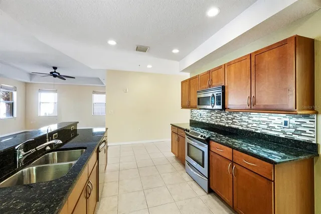 a kitchen with granite countertop stainless steel appliances a sink stove and cabinets