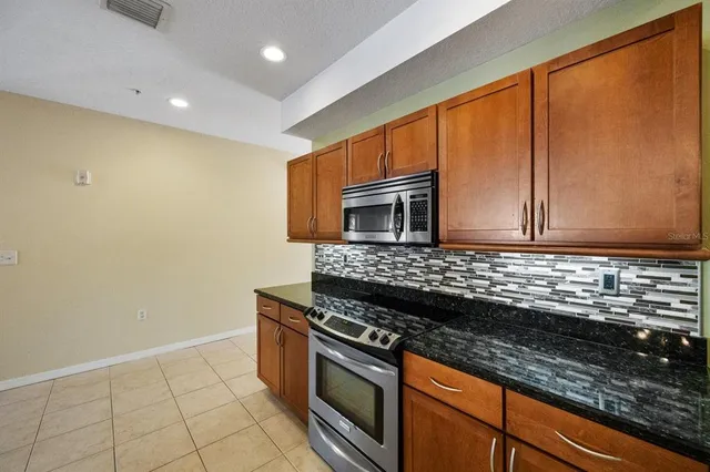 a kitchen with kitchen island granite countertop a stove top oven microwave and cabinets