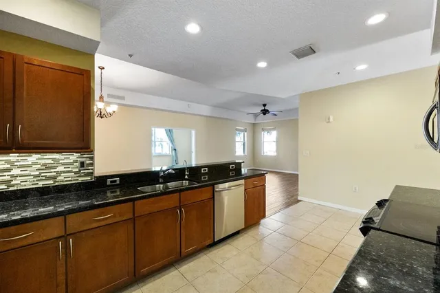 a large kitchen with granite countertop a sink and a stove top oven