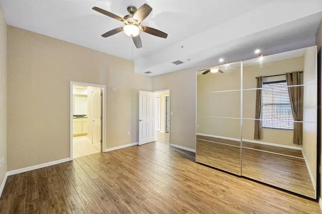 a view of empty room with wooden floor and fan