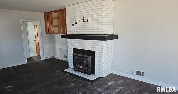 a view of an empty room with wooden floor and a fireplace