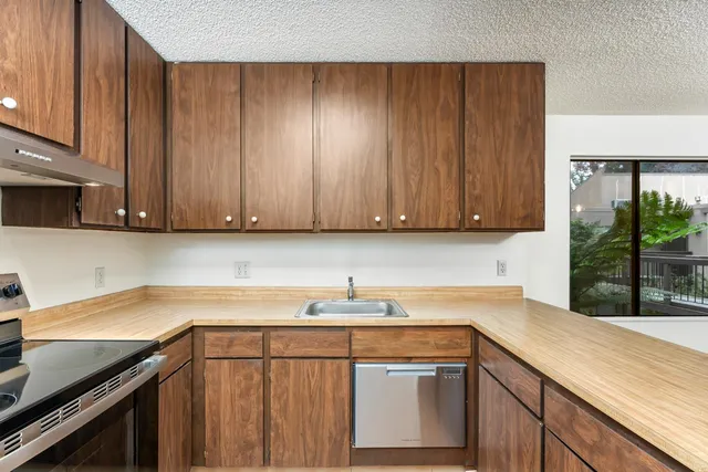 a kitchen with stainless steel appliances granite countertop wooden cabinets a sink and a stove