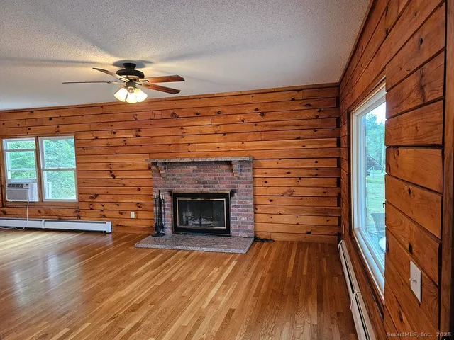 a view of an empty room with wooden floor fireplace and a window