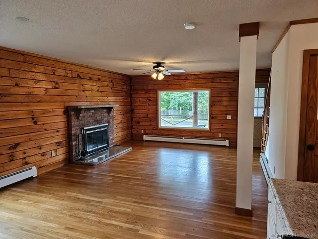 an empty room with wooden floor fireplace and windows