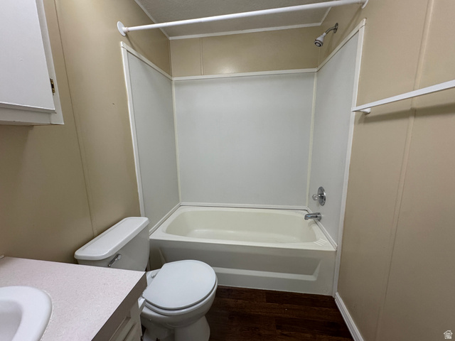 2491 Highway 89, Unit 315 Pleasant View, UT 84404 - Photo 33 of 34 Bathroom featuring a full tub and shower combination with a white surround, chrome fixtures, dark wood-finish flooring, and a white toilet