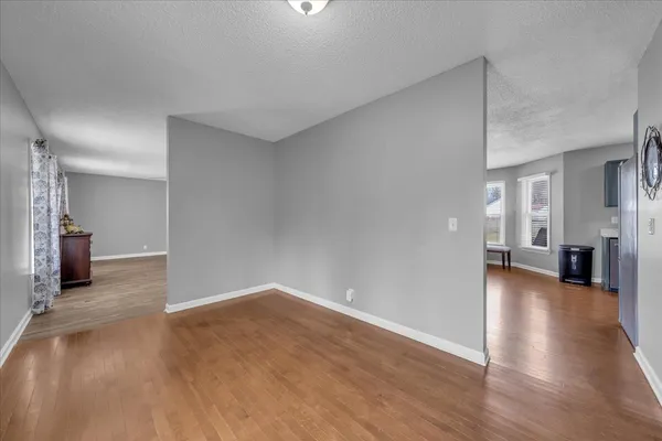 a view of a hallway with wooden floor and a bathroom