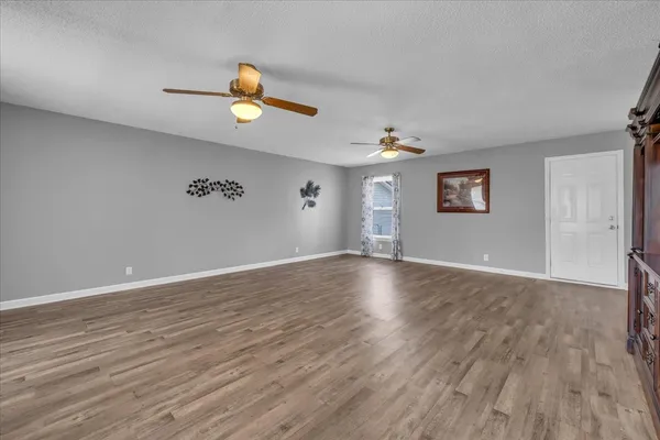 a view of an empty room with wooden floor and window