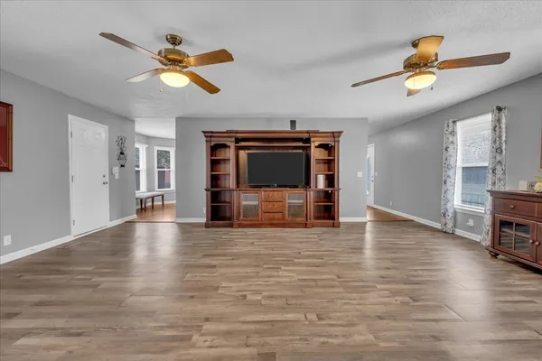 a view of empty room with wooden floor and fan