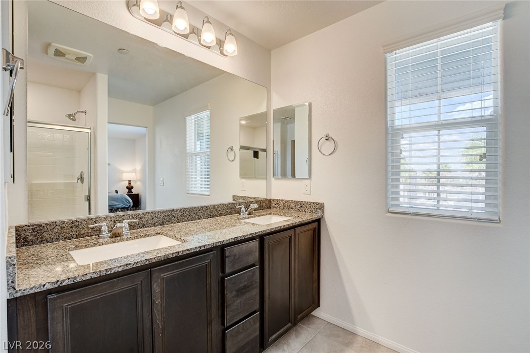 484 Filaree Place Henderson, NV 89015 - Photo 52 of 71 This primary bathroom offers dual sinks, granite countertops, and a glass-enclosed shower.
