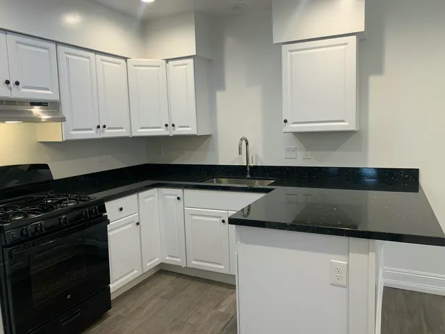 a kitchen with granite countertop white cabinets and black appliances