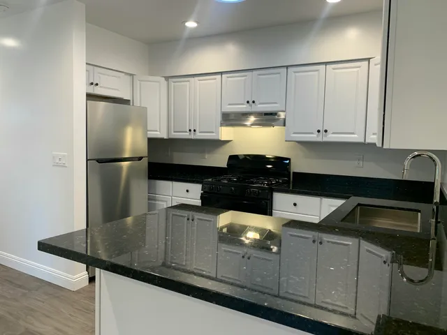 a kitchen with kitchen island granite countertop a sink a stove and refrigerator