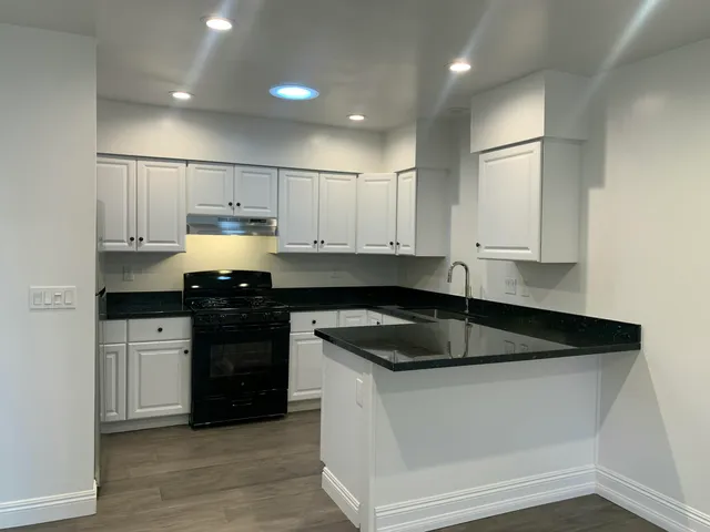 a kitchen with granite countertop white cabinets and black appliances