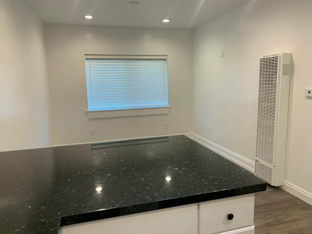 a view of an empty room with wooden floor and cabinets