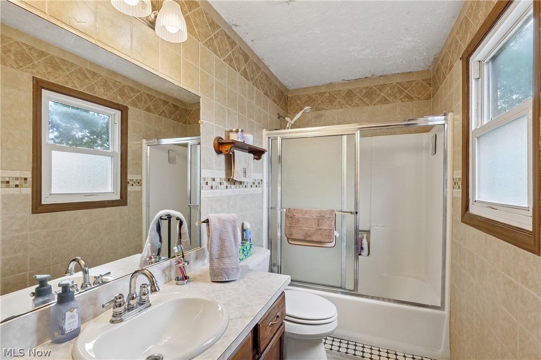 4702 Alger Road Richfield, OH 44286 - Photo 26 of 46 Second floor full bathroom with sink, vanity, tile walls, shower / tub combo with sliding glass doors, commode and tile flooring
