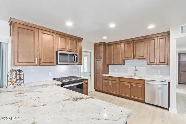 a kitchen with stainless steel appliances granite countertop a sink stove and refrigerator