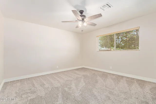 an empty room with a window and a fan