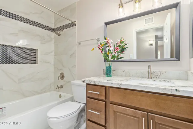 a bathroom with a granite countertop sink vanity mirror bathtub shower and a toilet