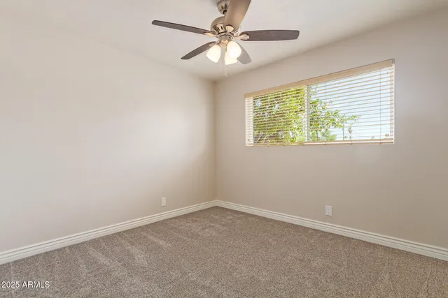 an empty room with a window and a fan