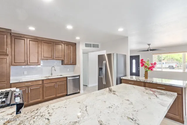 a kitchen with stainless steel appliances kitchen island granite countertop a refrigerator and a sink