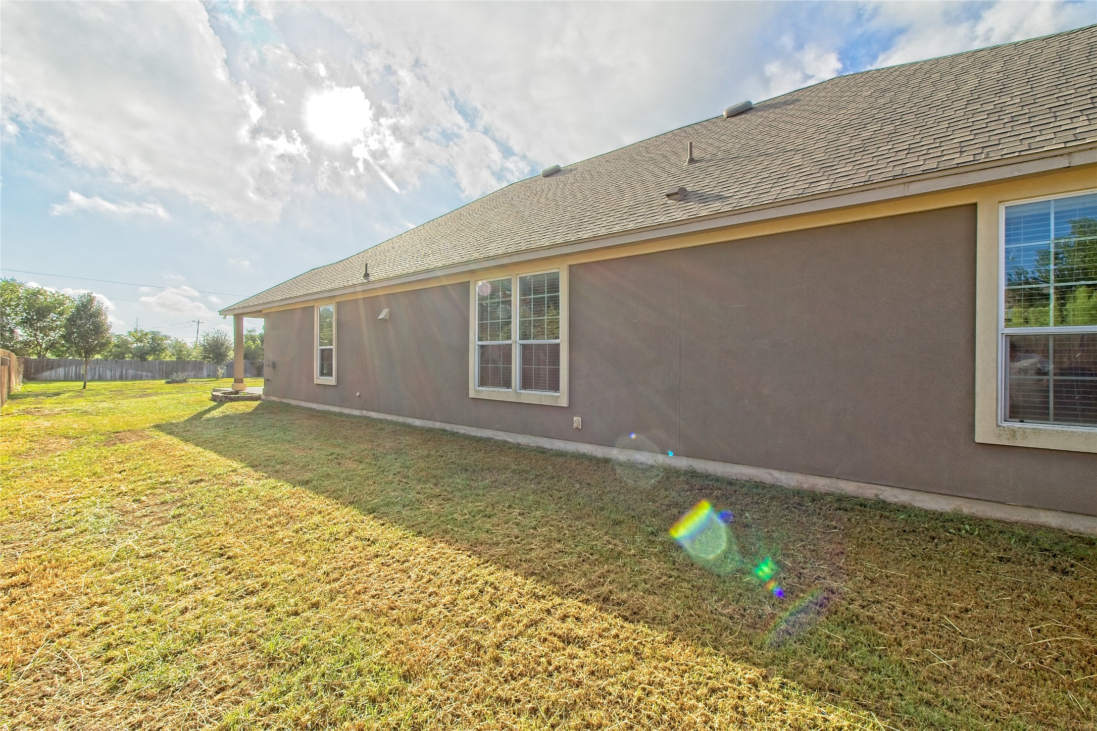 31443 Kingsway Road Georgetown, TX 78628 - Photo 24 of 40 A well-maintained lawn stretches beside the single-story structure, leading to a covered patio area.