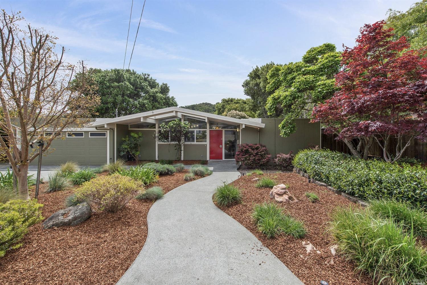 a front view of a house with a yard and potted plants