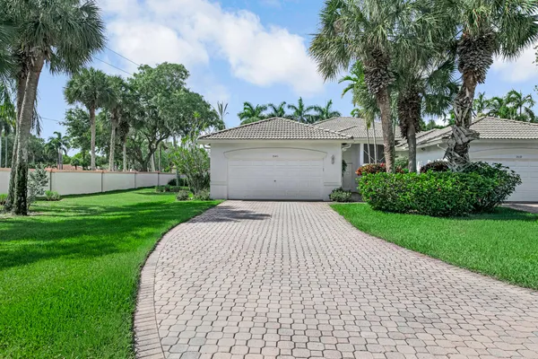 a front view of a house with a yard and palm trees