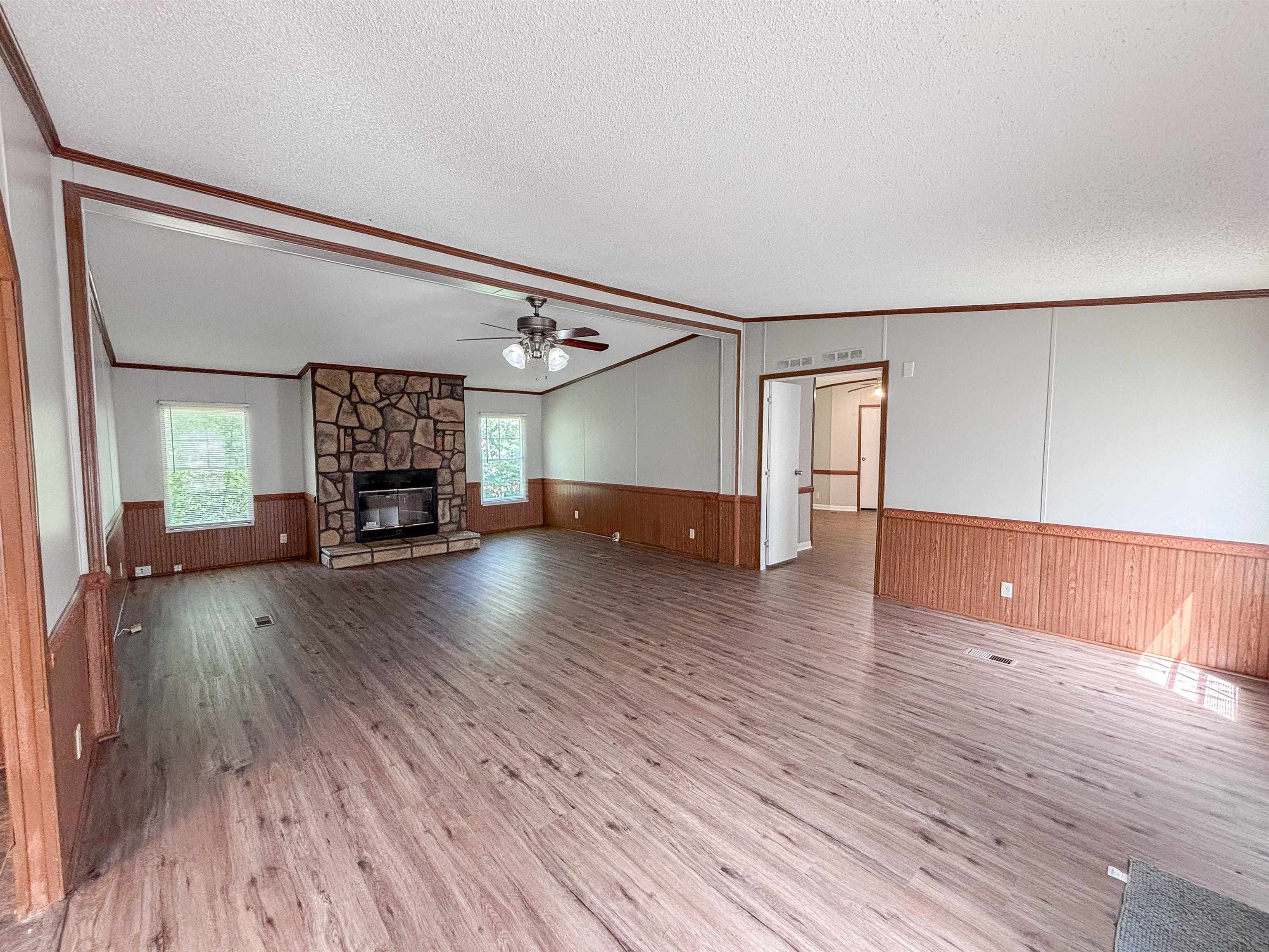 2847 Holly Grove Road Covington, TN 38019 - Photo 7 of 36 Expansive living room featuring wood-finish flooring, a stone-clad fireplace, and multiple windows