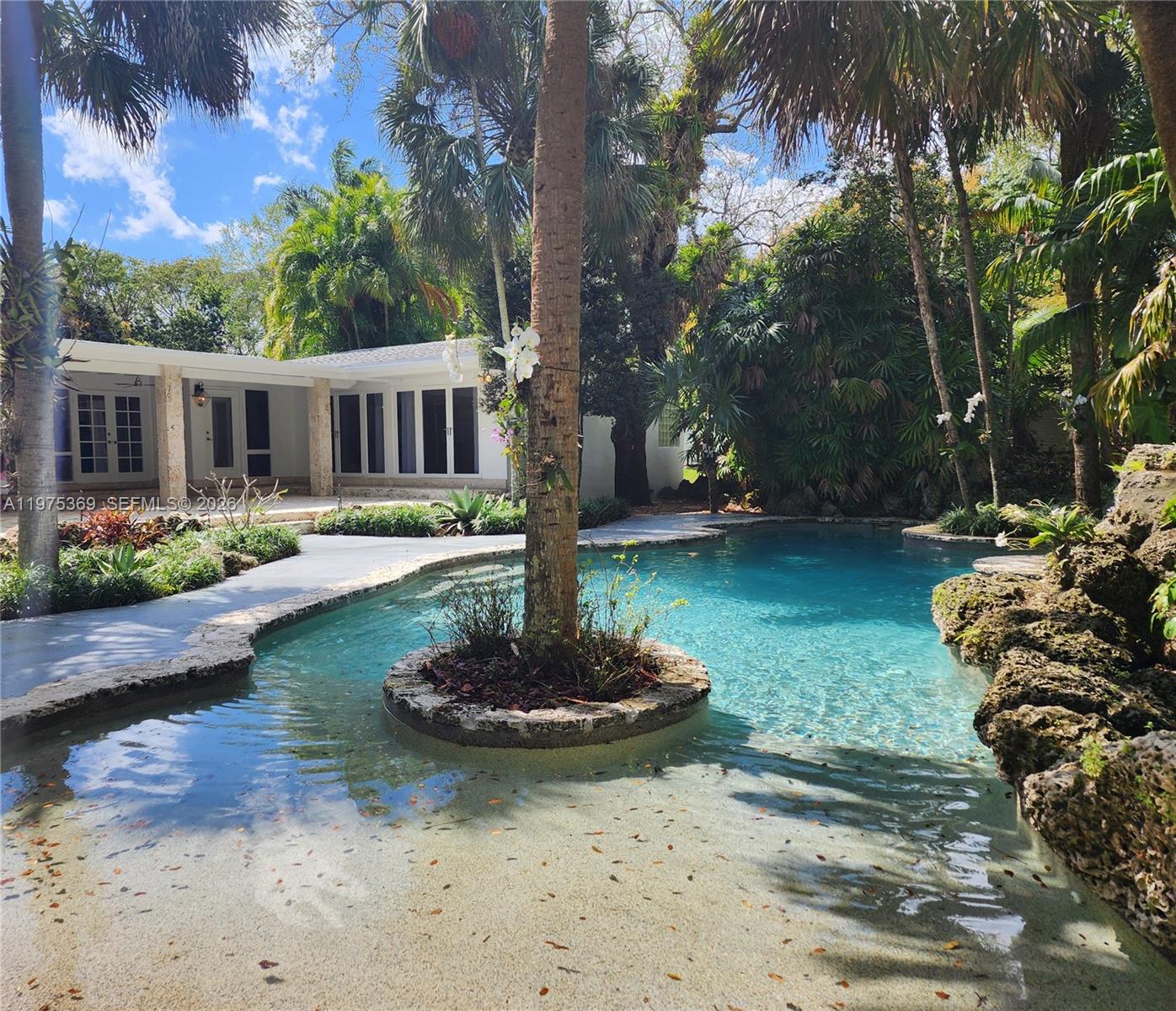 6065 Southwest 133rd Street Pinecrest, FL 33156 - Photo 25 of 41 a front view of a house with a yard swimming pool and outdoor seating