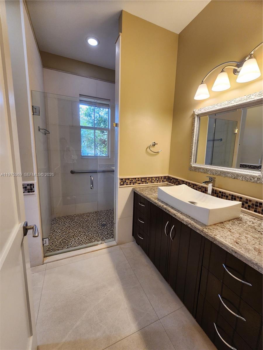 6065 Southwest 133rd Street Pinecrest, FL 33156 - Photo 40 of 41 a spacious bathroom with a granite countertop sink mirror and shower